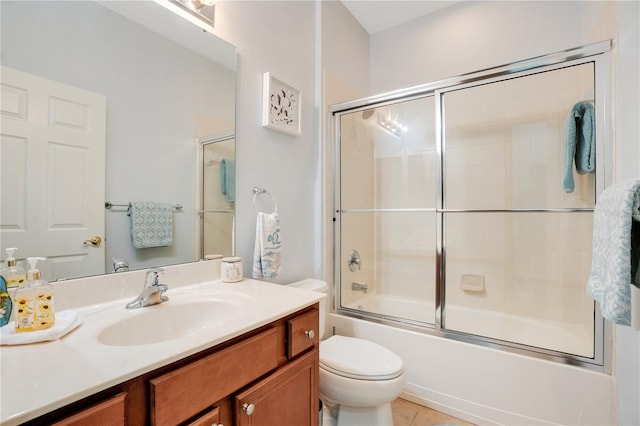 full bathroom featuring combined bath / shower with glass door, toilet, vanity, and tile patterned floors