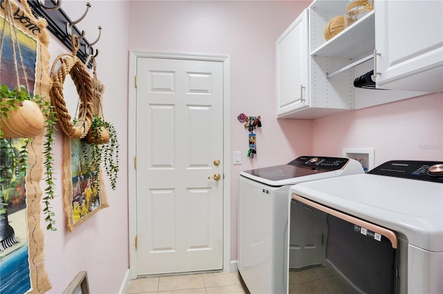 washroom featuring light tile patterned floors, cabinet space, baseboards, and washing machine and clothes dryer