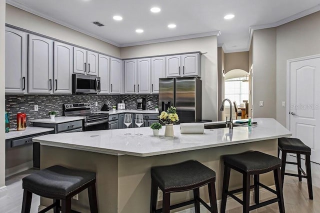 kitchen featuring a kitchen bar, visible vents, ornamental molding, a sink, and stainless steel appliances