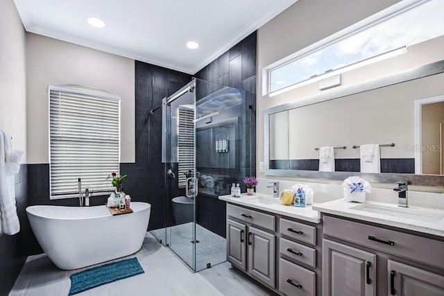 full bath featuring a freestanding bath, double vanity, ornamental molding, a stall shower, and a sink