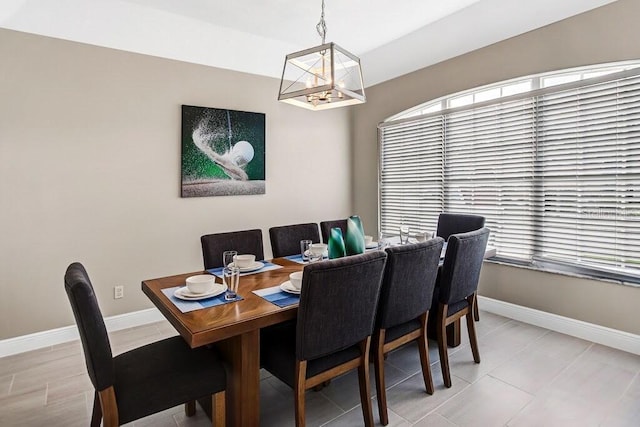 dining area with a wealth of natural light, a notable chandelier, and baseboards