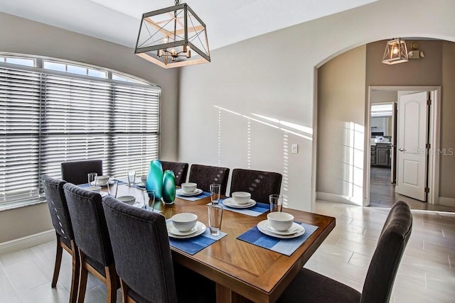 dining room featuring baseboards, arched walkways, and a notable chandelier