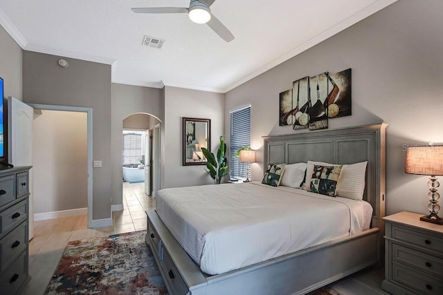 bedroom with visible vents, arched walkways, ceiling fan, ensuite bathroom, and crown molding