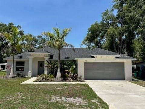120 S Chandler Ave, Deland, FL 32724 - view of front of house featuring a garage, driveway, a front lawn, and stucco siding
