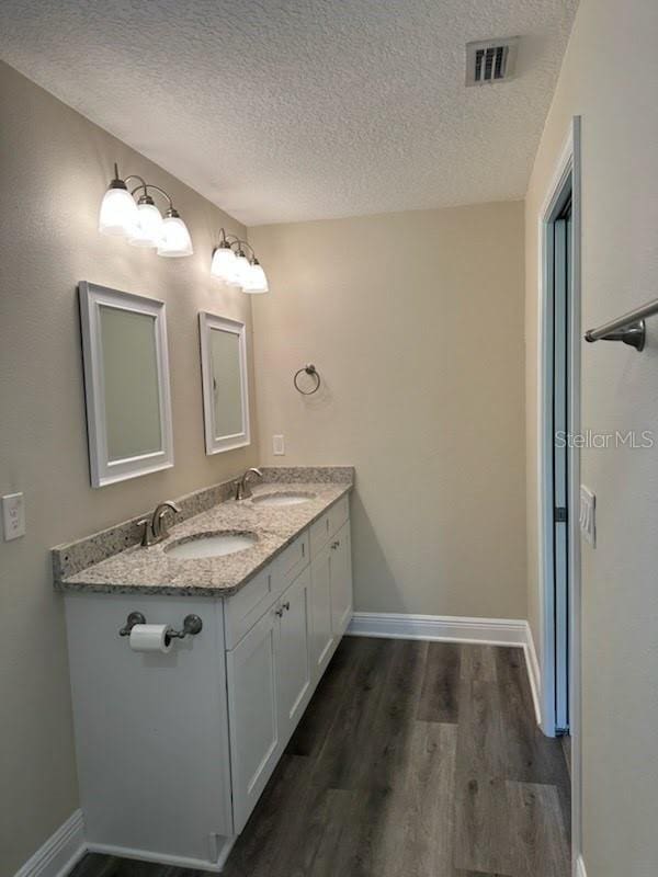 120 S Chandler Ave, Deland, FL 32724 - bathroom with a textured ceiling, wood finished floors, baseboards, and double vanity