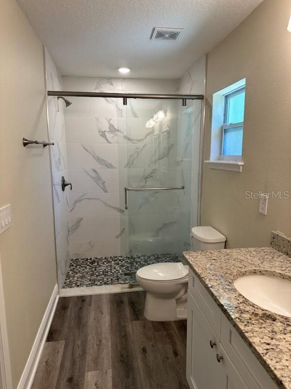 120 S Chandler Ave, Deland, FL 32724 - full bathroom with wood finished floors, a marble finish shower, toilet, a textured ceiling, and vanity