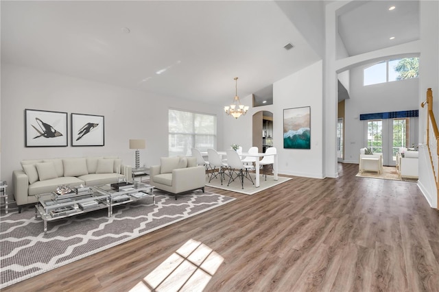 living room featuring arched walkways, a notable chandelier, wood finished floors, and high vaulted ceiling