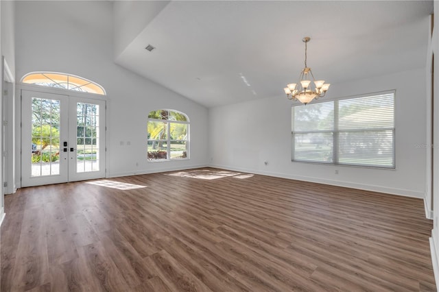 interior space with a notable chandelier, high vaulted ceiling, wood finished floors, french doors, and baseboards