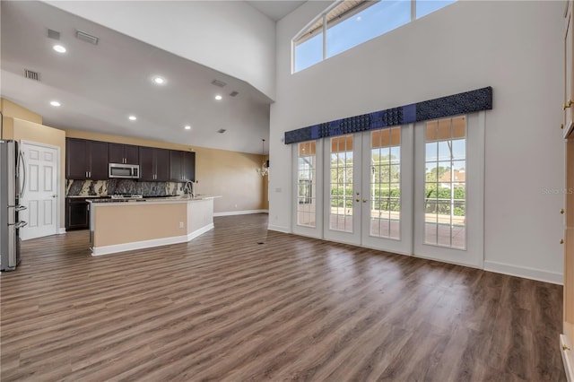 unfurnished living room with a sink, visible vents, baseboards, and wood finished floors