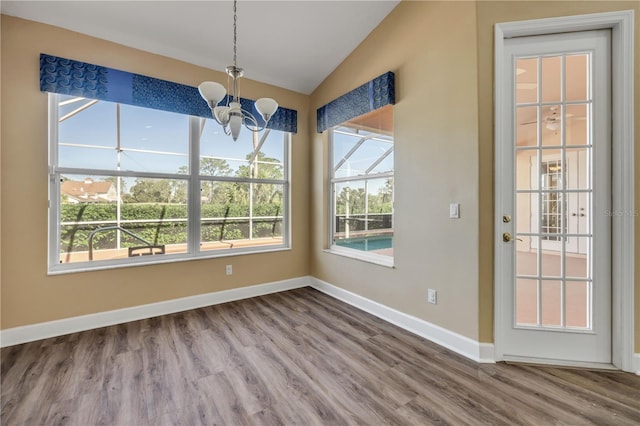 unfurnished dining area featuring a chandelier, a healthy amount of sunlight, baseboards, and lofted ceiling