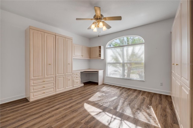 unfurnished bedroom with baseboards, a ceiling fan, wood finished floors, and built in desk