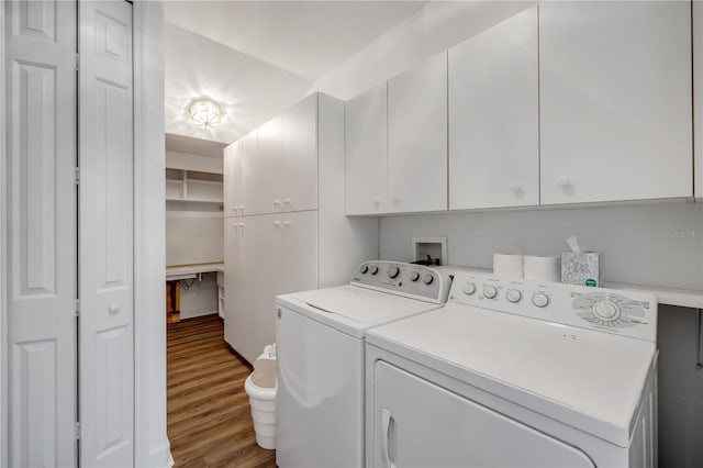 clothes washing area featuring washer and clothes dryer, cabinet space, and wood finished floors