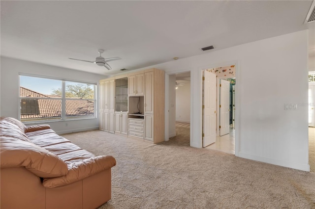 living room featuring visible vents, a ceiling fan, light colored carpet, and baseboards