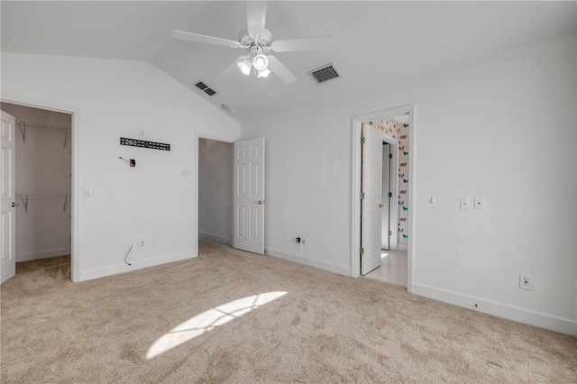 unfurnished bedroom featuring visible vents, carpet flooring, a walk in closet, and lofted ceiling