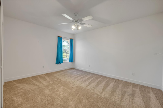 carpeted empty room with baseboards and a ceiling fan