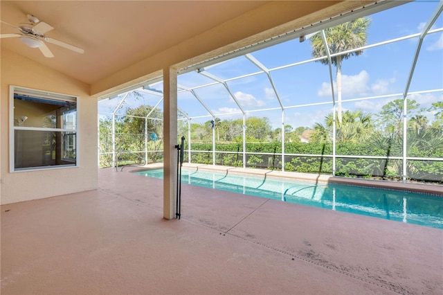 pool with glass enclosure, a patio area, and ceiling fan