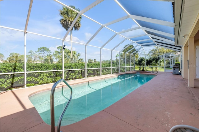 outdoor pool featuring glass enclosure, a patio, and grilling area