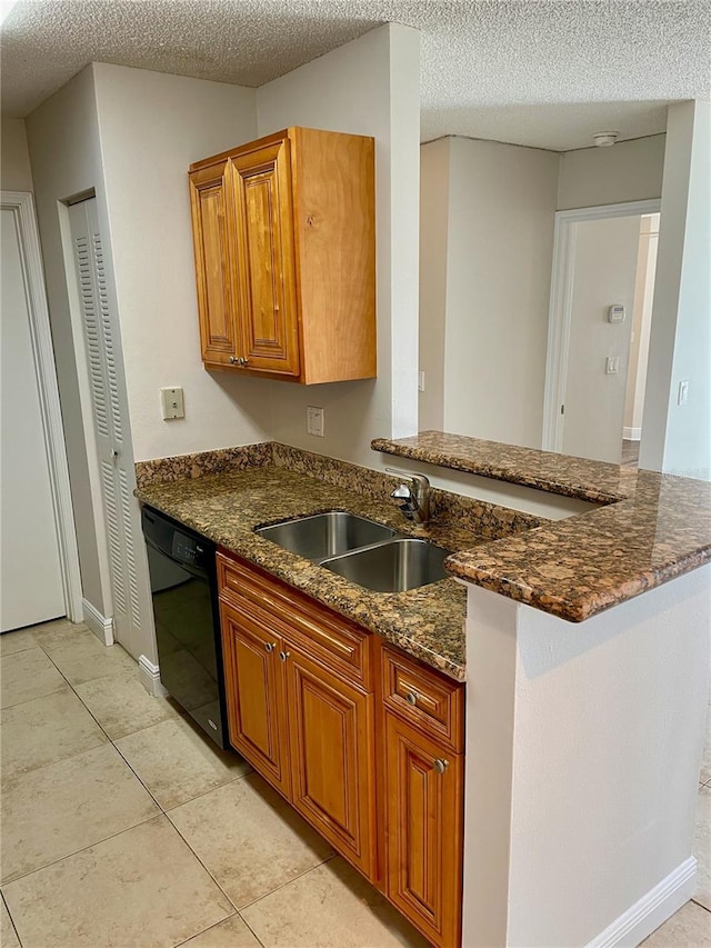 kitchen with dark stone countertops, brown cabinets, dishwasher, and a sink