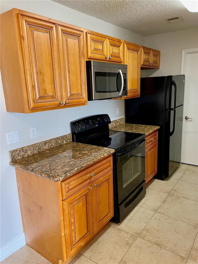 kitchen with a textured ceiling, stainless steel microwave, black electric range oven, and brown cabinets