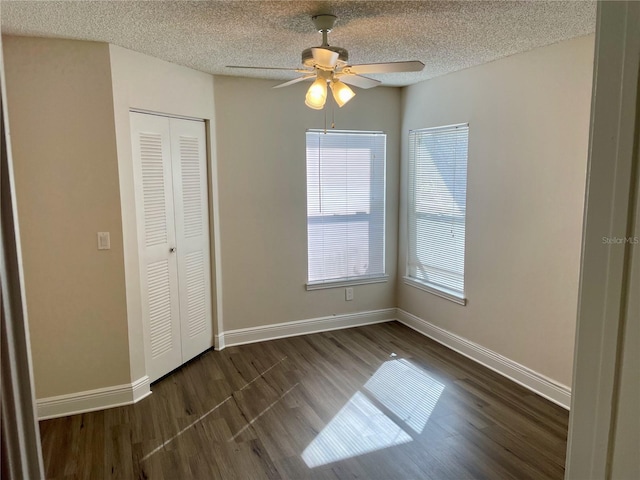 unfurnished bedroom with a closet, baseboards, a textured ceiling, and dark wood finished floors