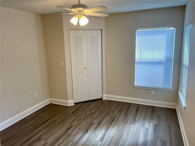 unfurnished bedroom with baseboards, dark wood-style flooring, a closet, and a textured ceiling