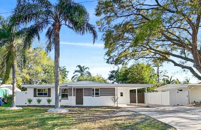 single story home featuring stucco siding, an attached carport, concrete driveway, and fence