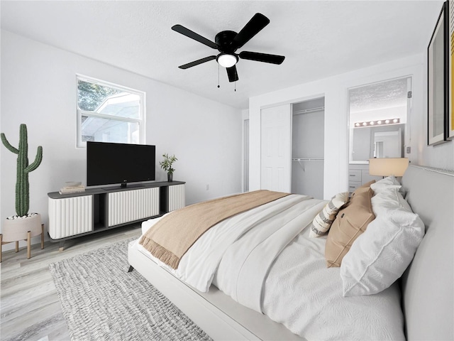 bedroom featuring light wood finished floors, ceiling fan, ensuite bath, and a closet