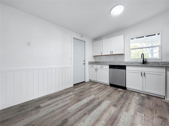 kitchen featuring light stone countertops, a wainscoted wall, white cabinetry, dishwasher, and light wood-type flooring