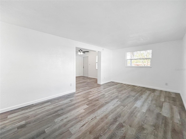 spare room featuring wood finished floors, baseboards, and ceiling fan