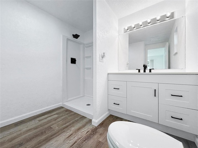 full bath featuring a textured wall, a shower stall, baseboards, and wood finished floors