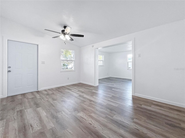 empty room with baseboards, wood finished floors, a ceiling fan, and vaulted ceiling