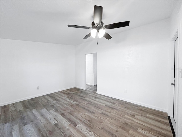 spare room featuring baseboards, wood finished floors, and ceiling fan