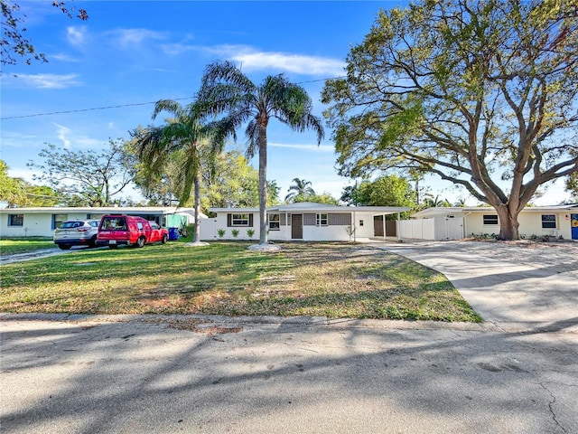 ranch-style house with concrete driveway and a front yard