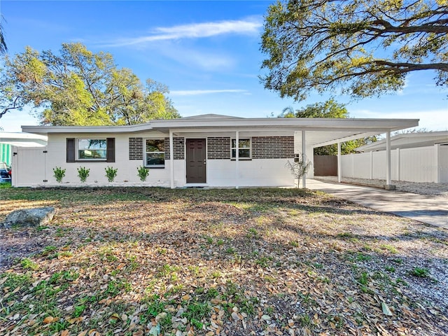 ranch-style home featuring an attached carport, driveway, and fence