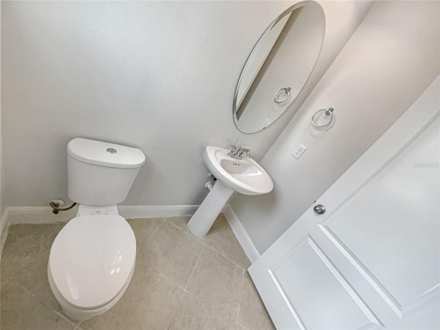 half bathroom featuring tile patterned floors, toilet, and baseboards