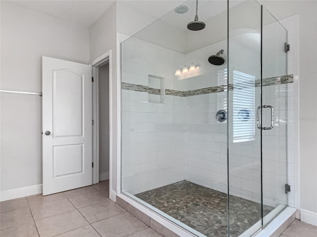 full bath with tile patterned flooring, a stall shower, and baseboards