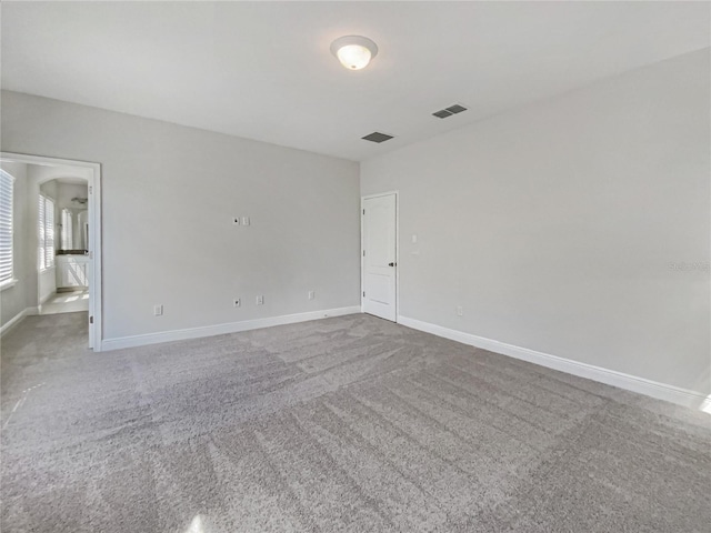 carpeted spare room featuring visible vents and baseboards