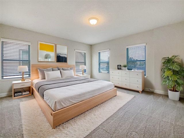 bedroom featuring multiple windows, baseboards, and light carpet