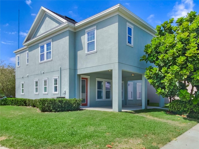 back of property with a patio area, a lawn, and stucco siding