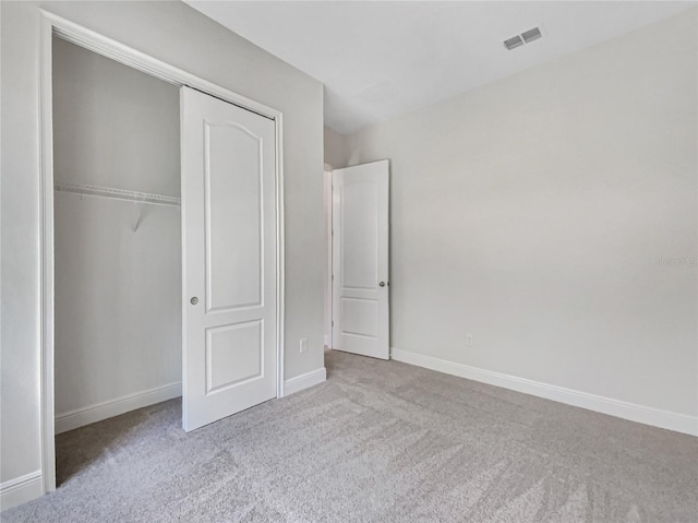 unfurnished bedroom with a closet, visible vents, carpet flooring, and baseboards