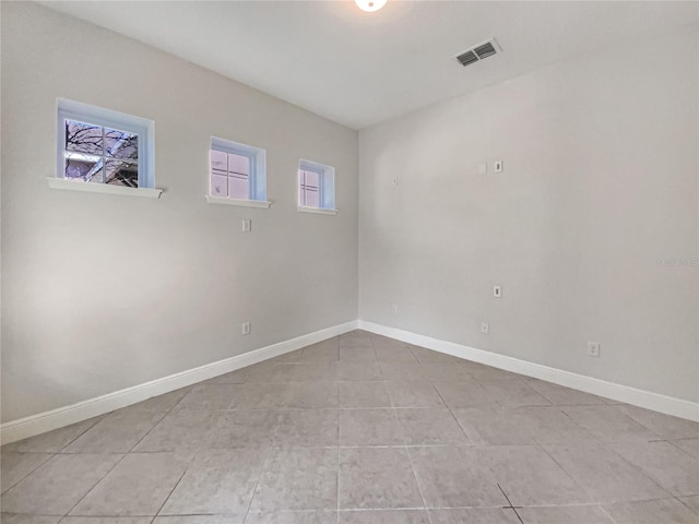 unfurnished room featuring light tile patterned floors, visible vents, and baseboards