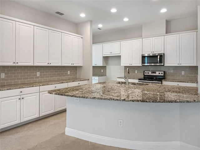 kitchen featuring visible vents, stone countertops, a sink, white cabinets, and appliances with stainless steel finishes