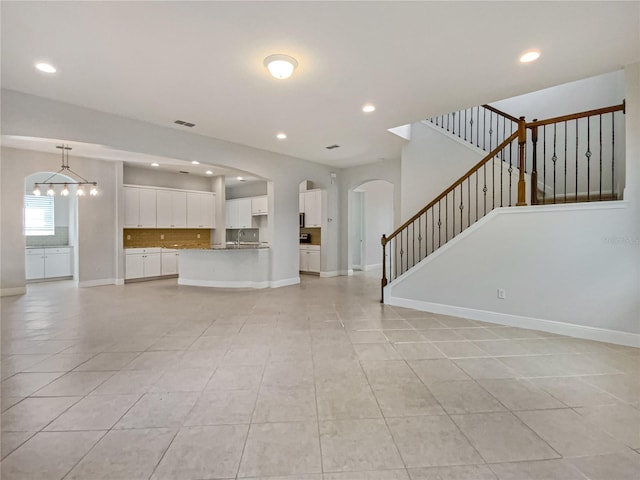 unfurnished living room featuring arched walkways, recessed lighting, and baseboards