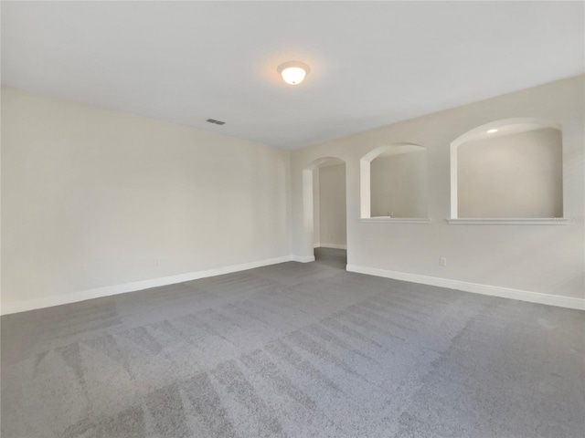 unfurnished room with visible vents, baseboards, and dark colored carpet