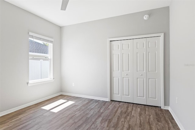 unfurnished bedroom featuring a ceiling fan, wood finished floors, baseboards, and a closet