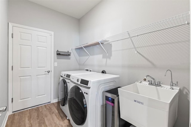 washroom with washer and clothes dryer, laundry area, light wood-style flooring, and a sink