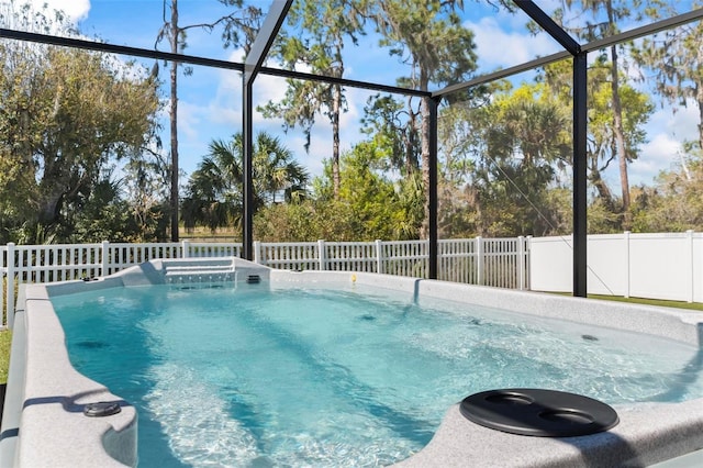 view of swimming pool with a lanai and fence