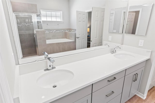 bathroom with double vanity, a shower stall, and a sink