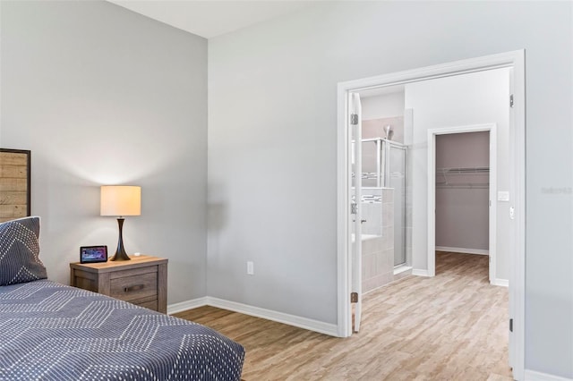 bedroom with a walk in closet, wood finished floors, baseboards, and a closet