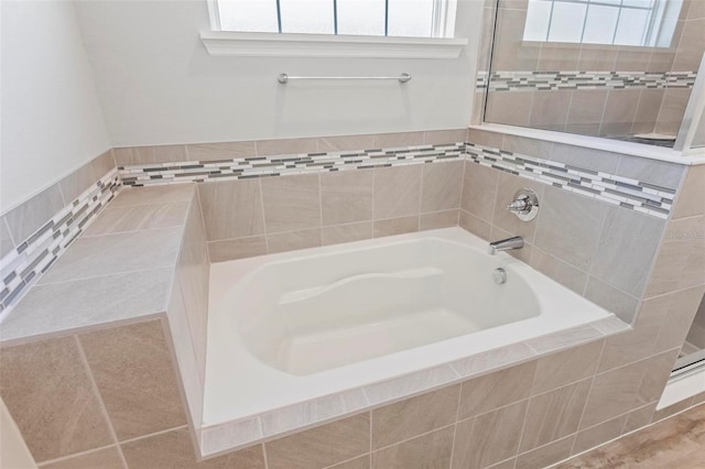 full bath featuring a bath, a healthy amount of sunlight, and a tile shower